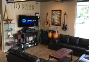 Big room with sofa, mounted tv, and 3d cigars sign on table